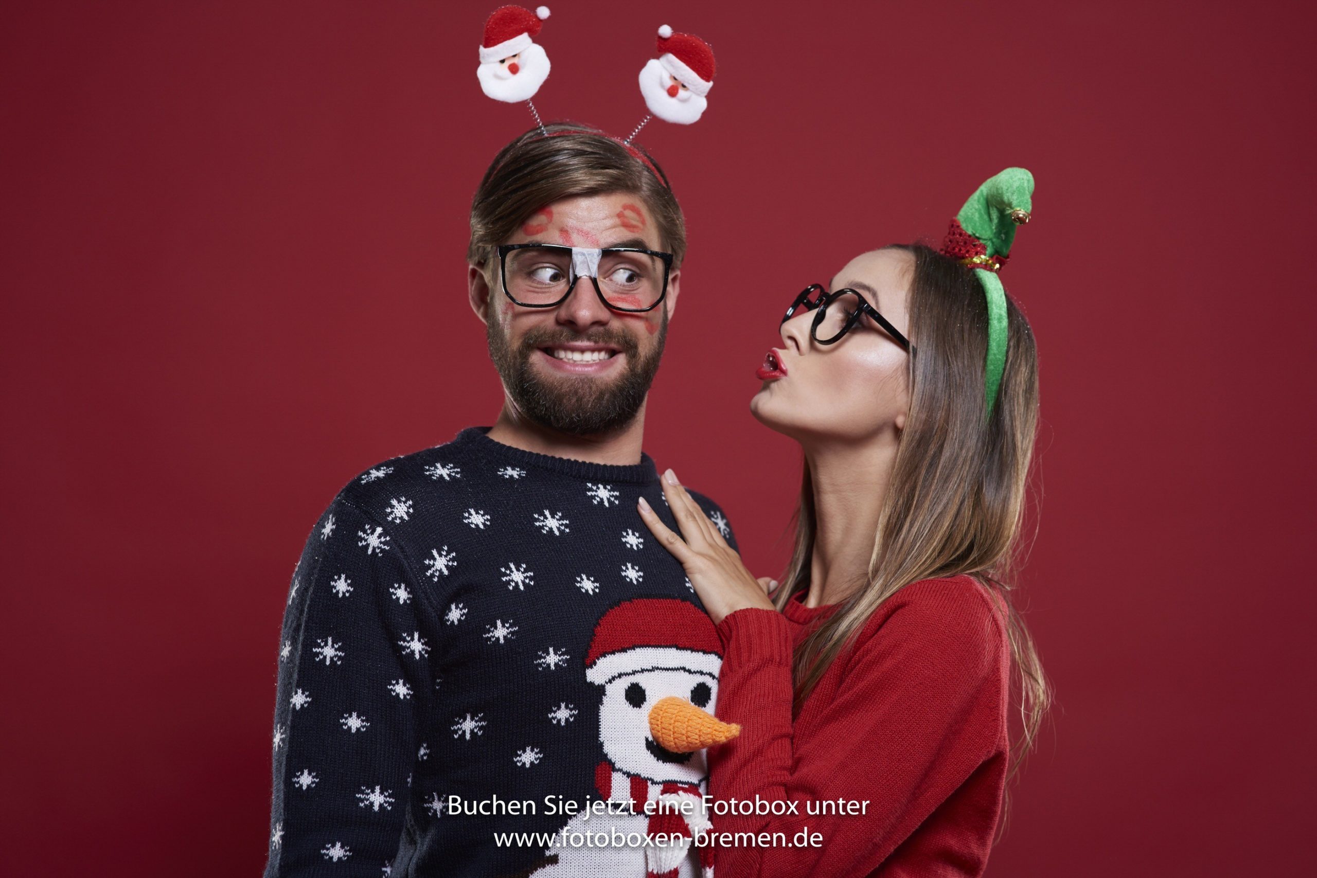 Frau und Mann machen lustige Fotos vor der Fotobox auf der Weihnachtsfeier